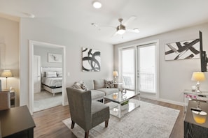 A modern living room with a sofa, armchair, coffee table, and artwork on the walls. - MCK211 | McKinney Corporate 2BD | Pool | Workspace (McKinney)