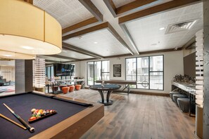 A pool table with balls, a billiard cue, and a pool table with a wooden finish.