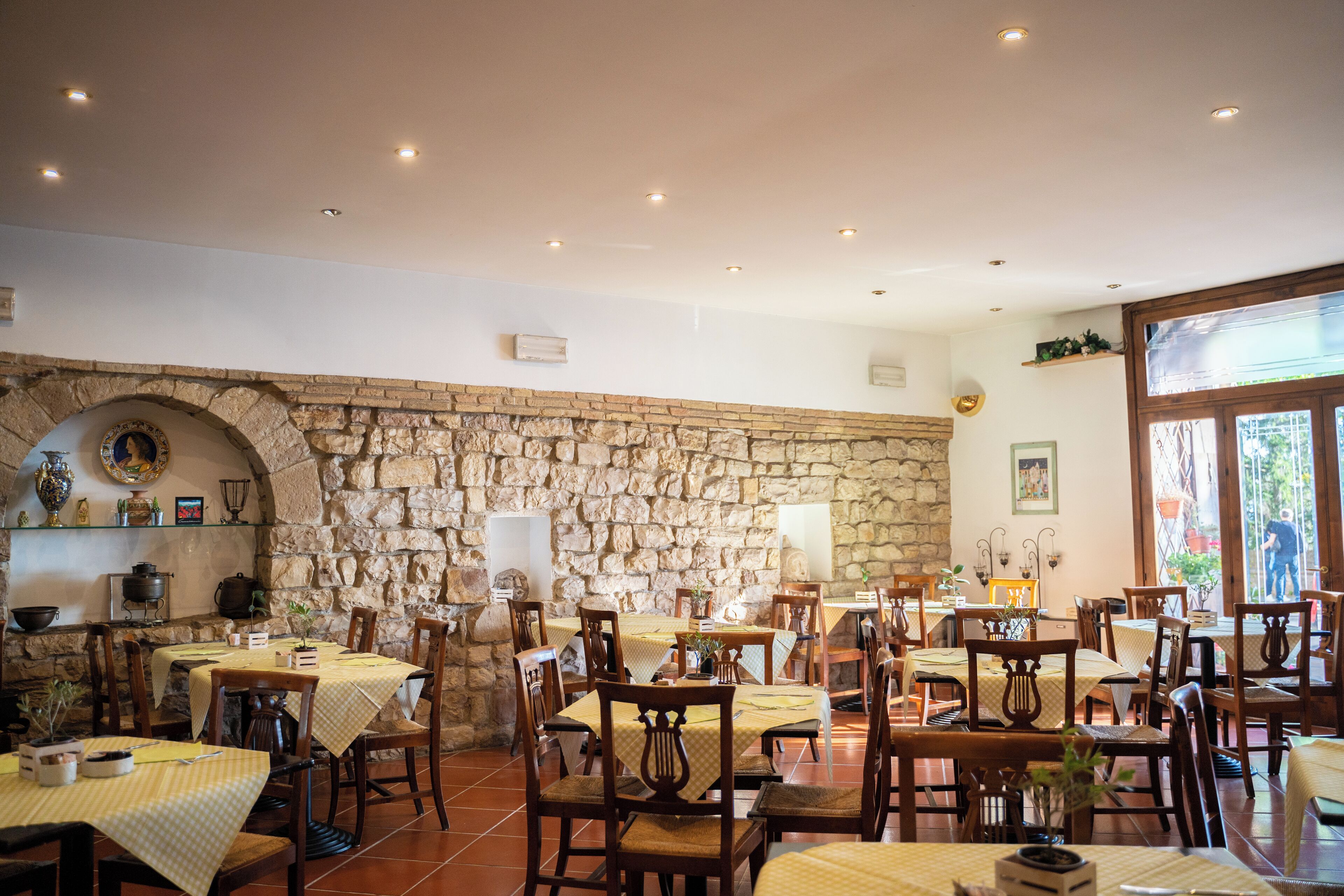 Un restaurante con paredes de piedra, varias mesas con manteles amarillos y sillas de madera.