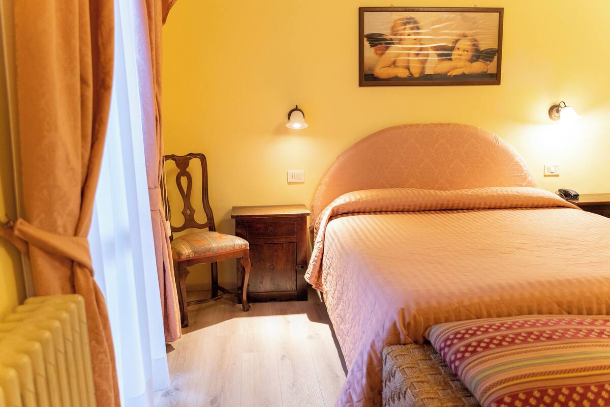 Ein Schlafzimmer mit Bett, Stuhl, Nachttisch und Wandlampe.