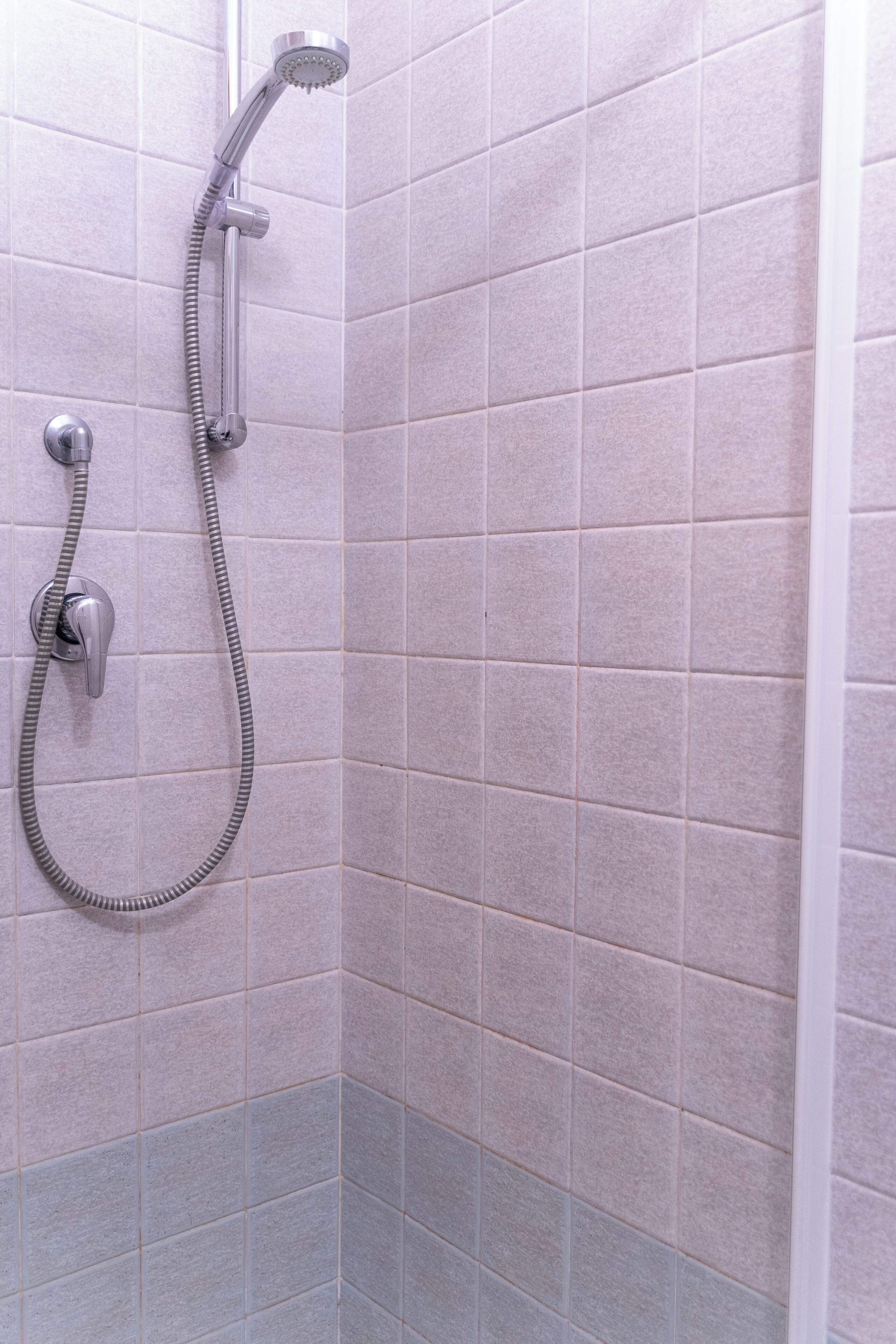Un área de ducha con un cabezal de ducha manual y otro fijo en la pared.
