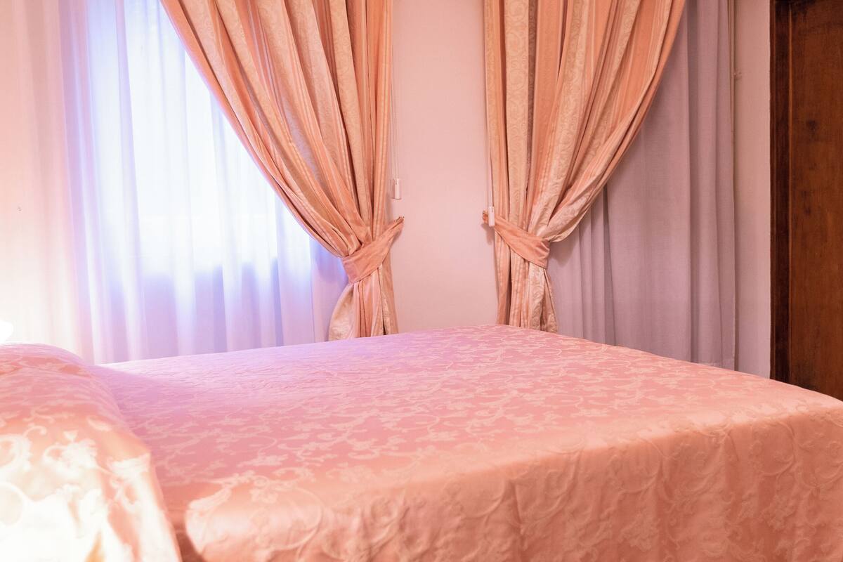Ein Schlafzimmer mit einem Bett, Vorhängen und einem Nachttisch aus Holz.