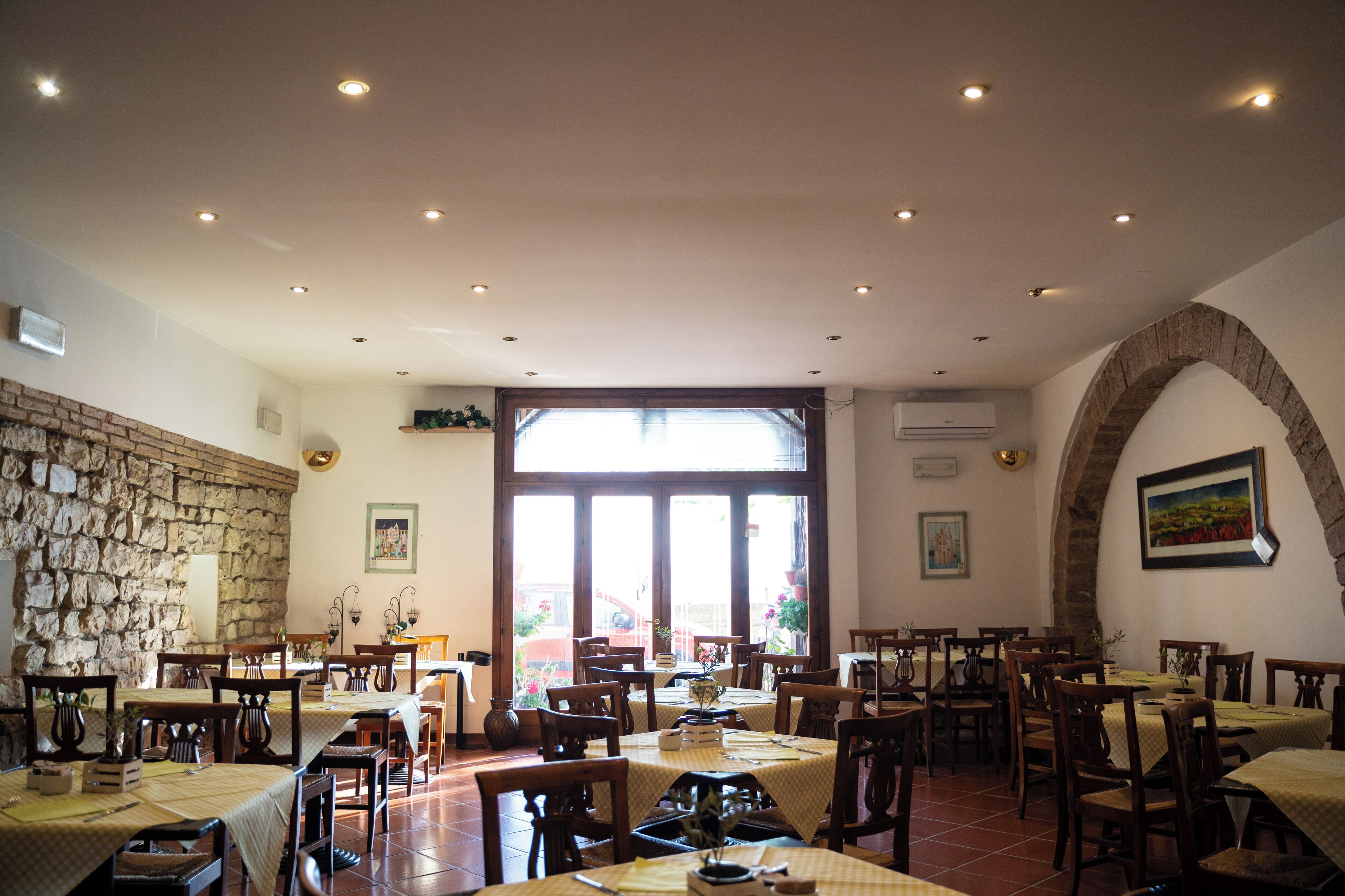 Un restaurante con varias mesas y sillas, una pared de piedra y un ventanal con vistas.