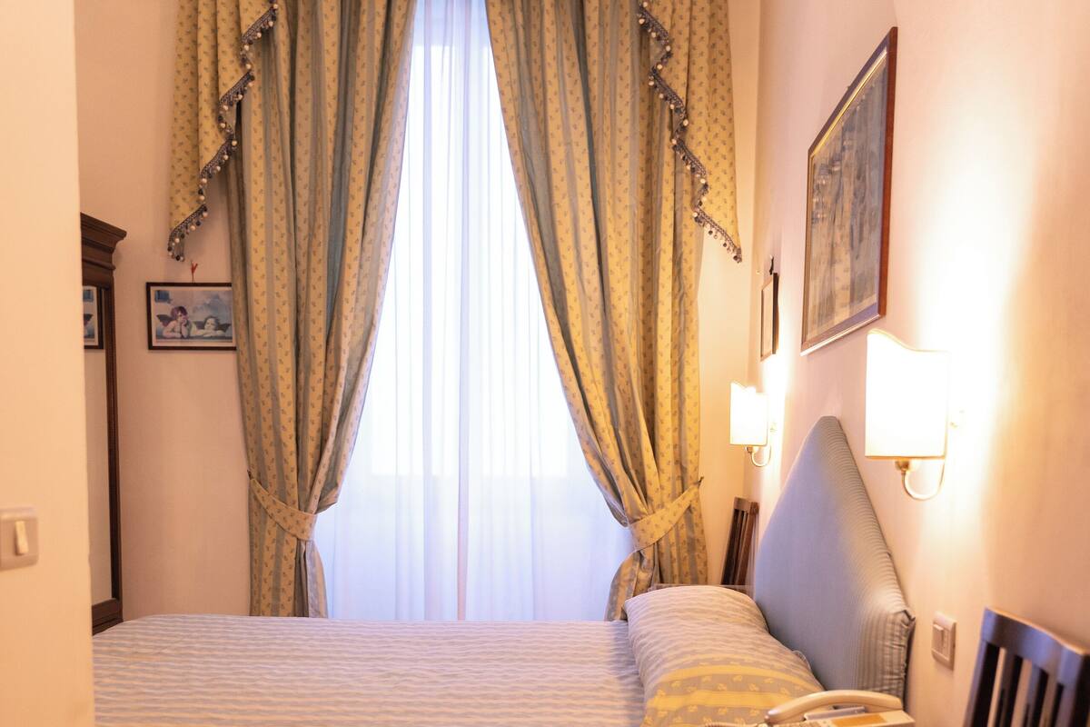 Ein Hotelzimmer mit Bett, Nachttisch, Lampe und Stuhl.