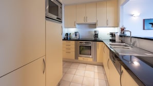 Una cocina moderna equipada con microondas, horno, cafetera y lavabo.