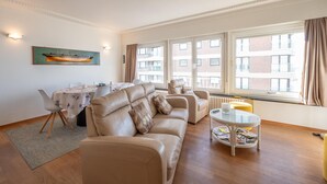 Una sala de estar moderna con un sofá beige, una mesa de centro de vidrio y un comedor con mesa y sillas.