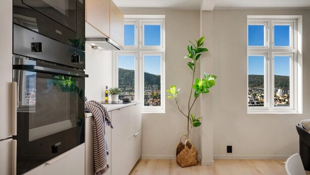 Cozinha moderna com uma janela grande, vista para o horizonte urbano e um vaso com planta.