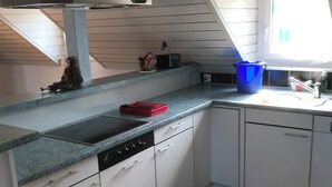 Une cuisine avec des armoires blanches, un plan de travail en granit, une cuisinière et une fenêtre.