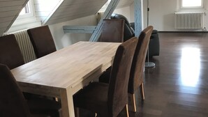 Une pièce mansardée avec une table et des chaises en bois, un radiateur et une fenêtre.