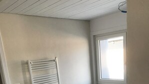 Une pièce avec un meuble blanc, un radiateur, une fenêtre et une porte.