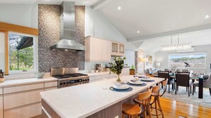 A modern kitchen with a large island, wooden cabinets, and a stone backsplash.