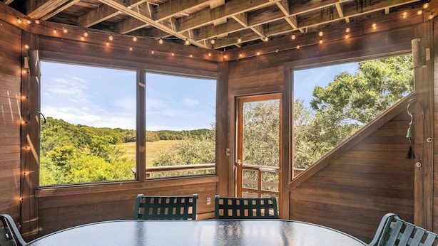 A wooden interior with large windows, a round table, and two chairs.