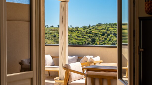 Ein Balkon mit Holzmöbeln und Blick auf eine grüne Landschaft.