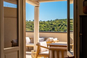 A balcony with wooden furniture and a view of a green landscape. - Casa Verga con Terrazza by Wonderful Italy (Noto)