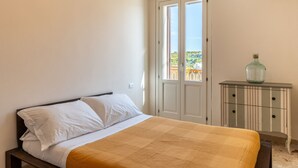 Ein Schlafzimmer mit einem Bett, einem Nachttisch und einer Tür, die auf einen Balkon führt.