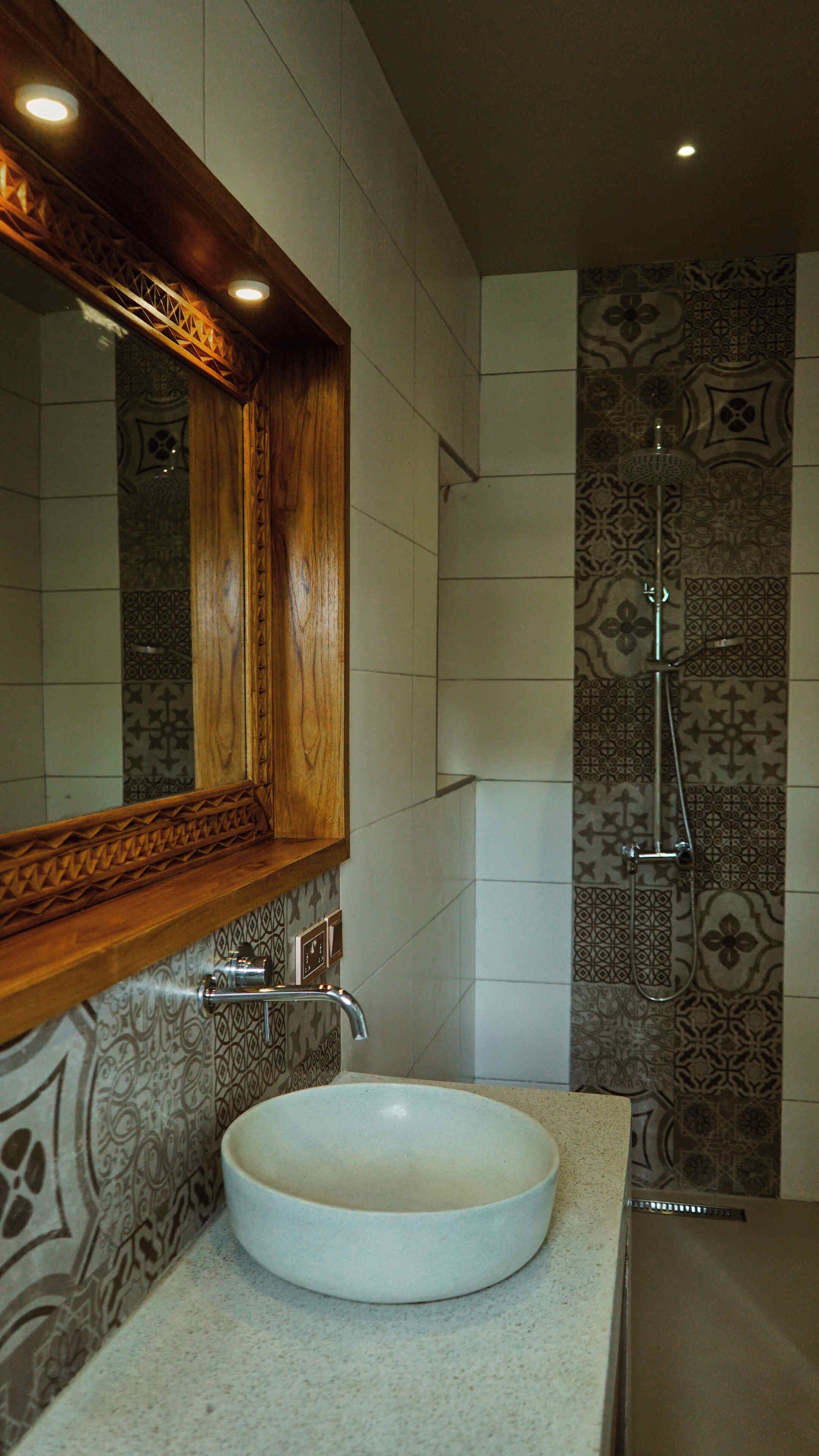 A bathroom with a wooden-framed mirror, a white sink, and patterned tiles.