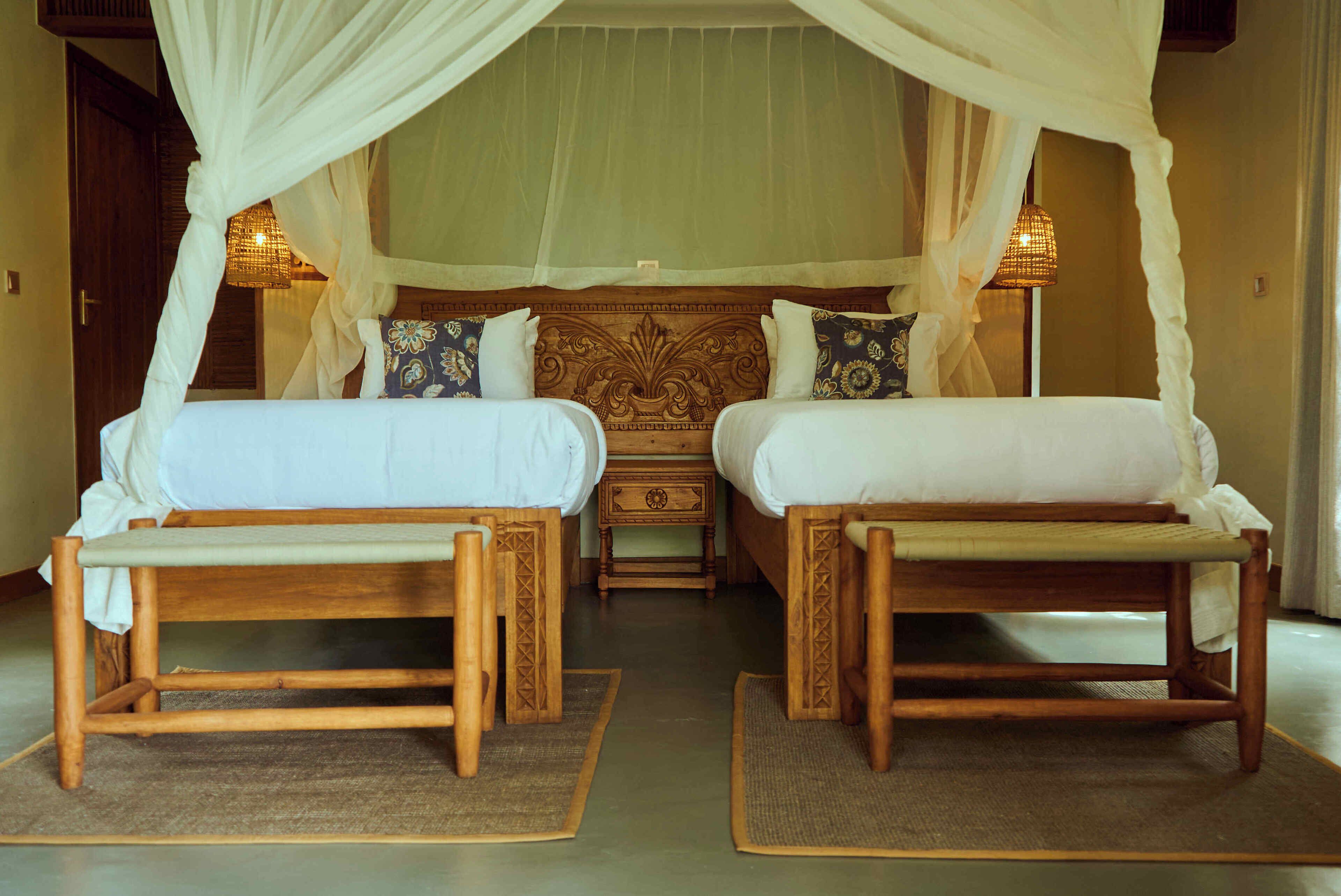 A room with two wooden beds, a nightstand, and a canopy bed with a decorative headboard.