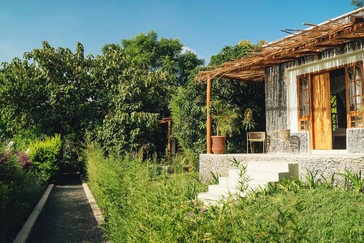 A house with a stone exterior, wooden porch, and a pathway leading to the entrance.