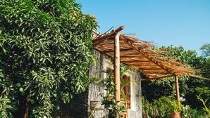 A rustic building with a thatched roof, surrounded by lush greenery and stone walls. - Mateves Boutique Lodge  (Arusha)