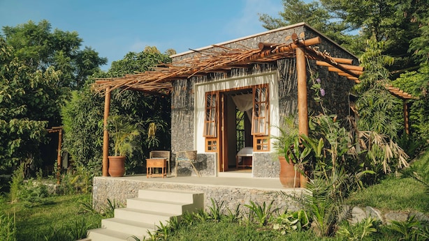 A small stone house with a wooden pergola, a set of stairs leading to the entrance, and a garden with various plants. - Mateves Boutique Lodge  (Arusha)
