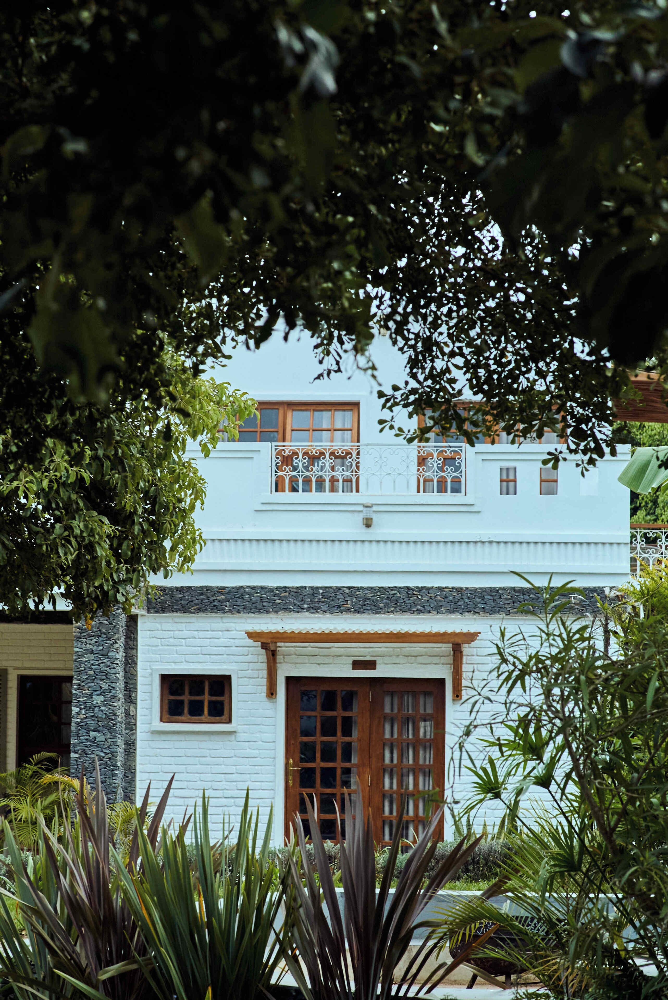 A two-story building with a white exterior, a wooden door, and a balcony with decorative railings.