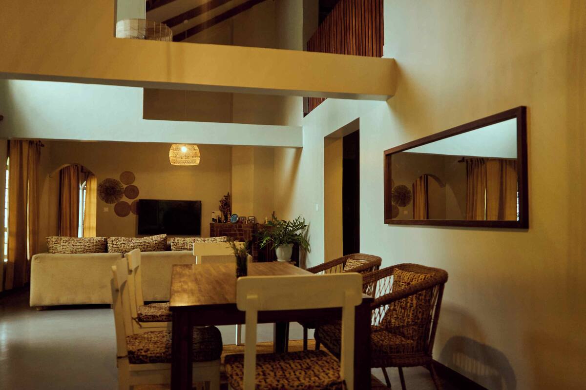 A spacious living area with a high ceiling, a dining table, and comfortable seating.
