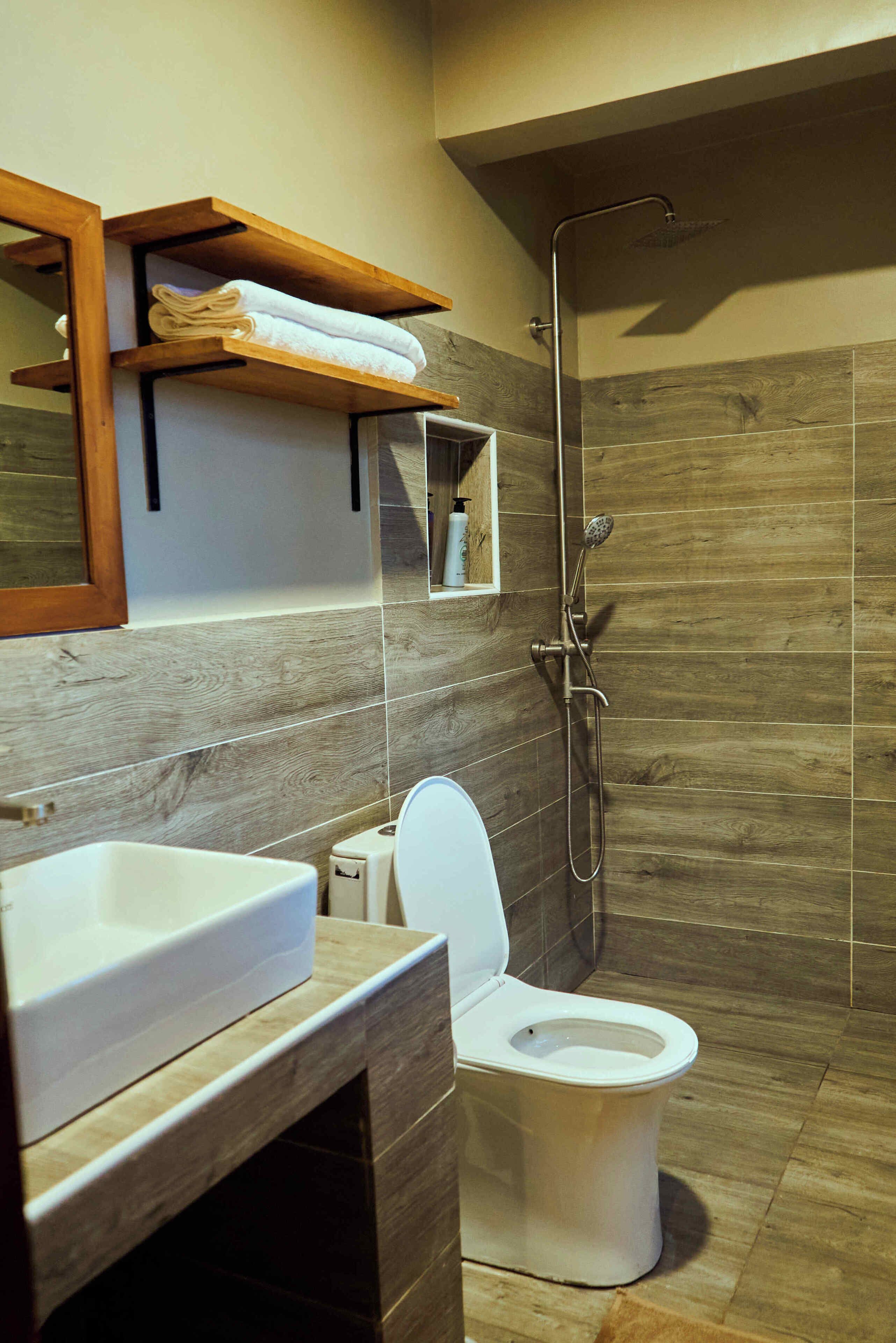 Un baño moderno con un mueble de tocador de madera, inodoro blanco y cabina de ducha.