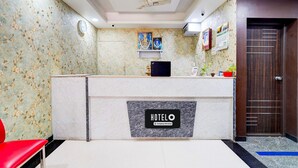 A hotel reception area with a marble reception desk, a clock, and a ceiling fan. - Super Hotel O Perungalathur (Chennai)
