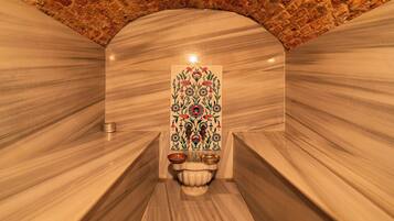 A spa room with marble walls, a decorative tile wall, and a small sink with two bowls.