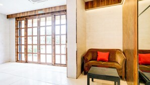 Un hall d’entrée spacieux, doté d’une grande porte en bois, d’un canapé avec des coussins rouges et d’une petite table.
