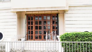 Un bâtiment doté d’une grande porte en bois, d’une façade blanche et d’une clôture en métal à l’avant.