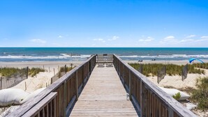 A wooden boardwalk leading to a beach with a clear sky. - Chasing Sunrises | Newly Rebuilt Luxury Oceanfront Retreat (Ocean Isle Beach)