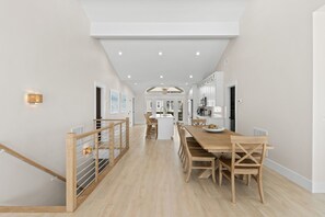 A modern kitchen with a central island, wooden dining table, and chairs.