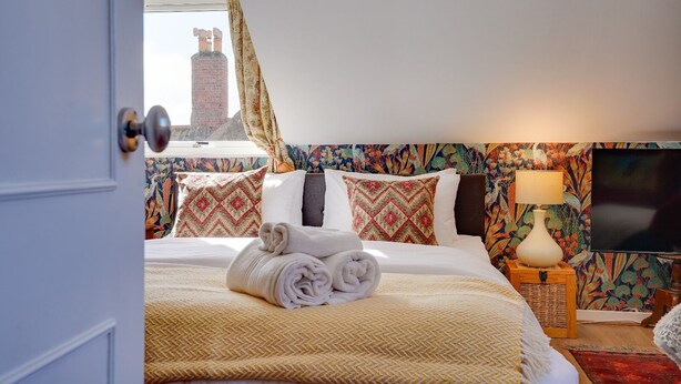 Een hotelkamer met een bed, een televisie, een lamp en uitzicht op een gebouw.