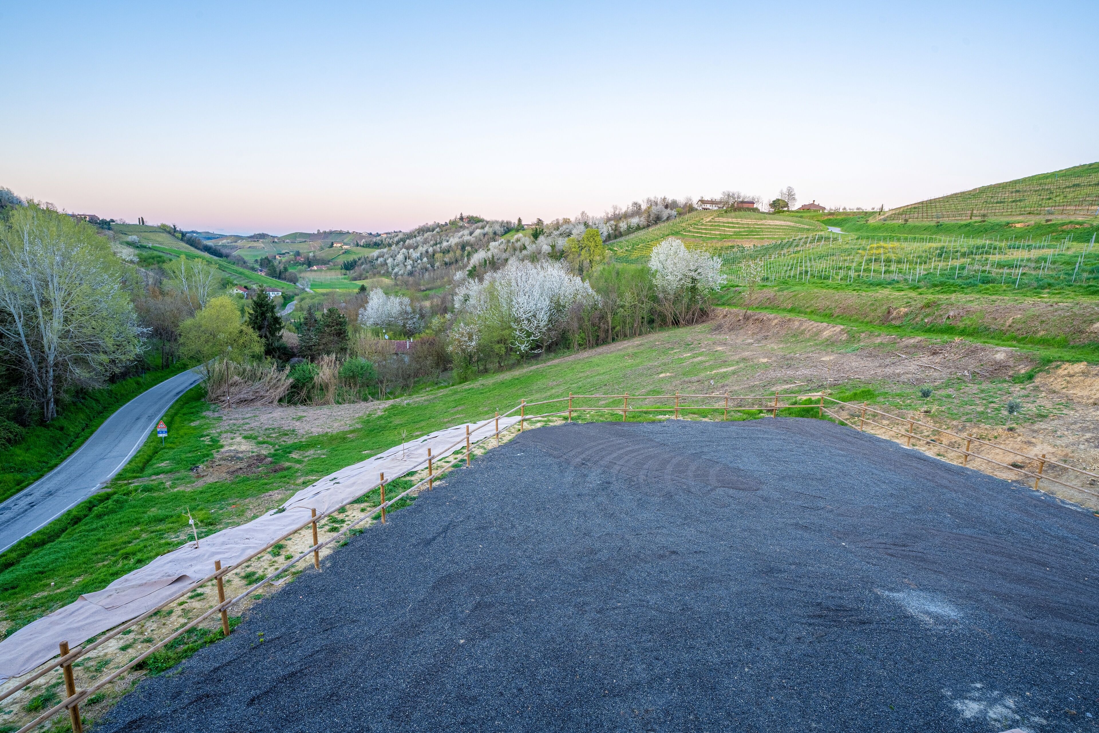 Paisatge rural amb una zona pavimentada, una carretera i una tanca.