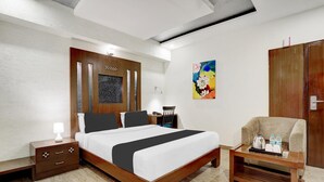 Ein Hotelzimmer mit einem hölzernen Bett, einem Nachttisch, einem Schreibtisch mit Stuhl, einem Bild an der Wand und einem Kleiderschrank.