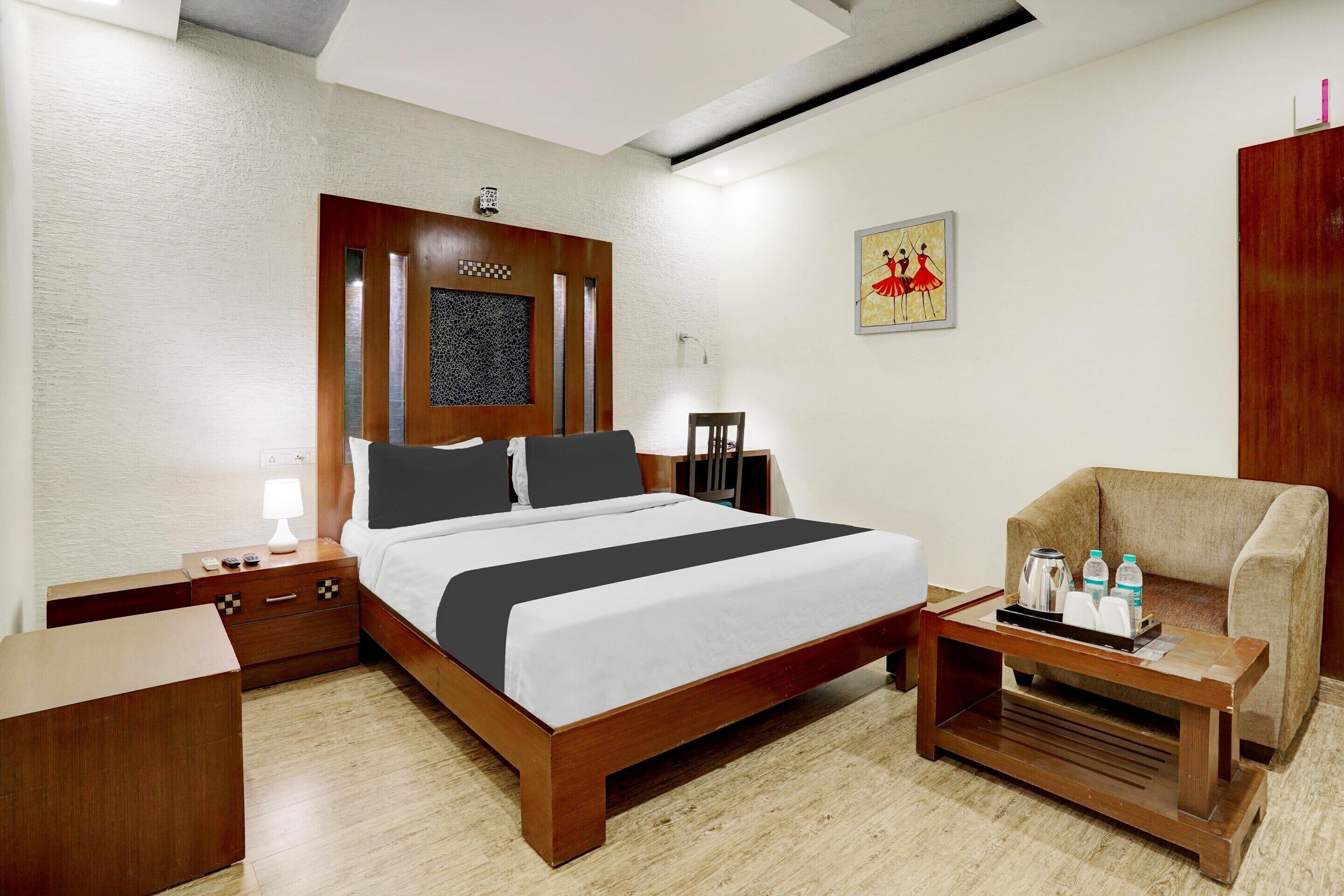 Hotelkamer met een houten bed, nachtkastje, een houten bijzettafeltje, een bank en een aan de muur bevestigde televisie.