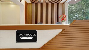 Ein Empfangsbereich mit einem Holzbüro, einer Uhr und einem Schild mit der Aufschrift 'TOWNHOUSE Company-Serviced'.