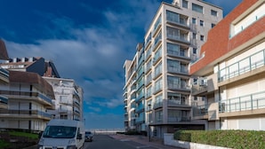 A modern residential street with multi-story buildings, a van, and a clear sky. - Apartment in Knokke-heist With Sea Views (Knokke-Heist)