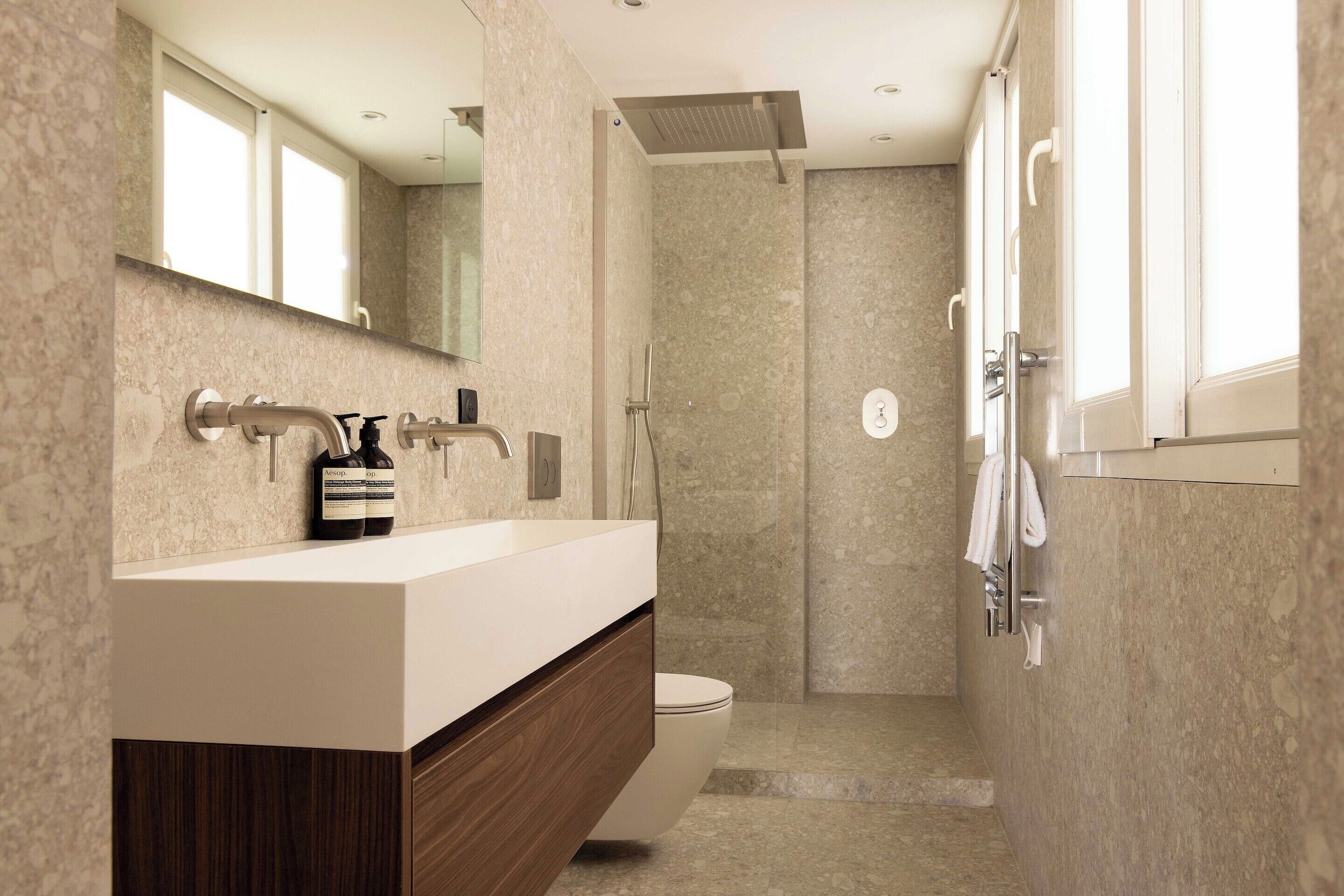 A modern bathroom with a marble countertop, a shower, and a toilet.