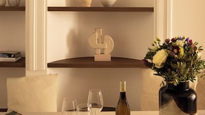 A table with a wine bottle and glasses, a book, and a vase with flowers.