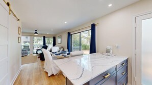 Habitación de hotel moderna con una cama grande, una zona de comedor con una mesa dispuesta para dos personas y una cocina con cafetera.