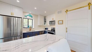 Una cocina moderna con electrodomésticos de acero inoxidable, encimera de mármol y una puerta corredera estilo granero.