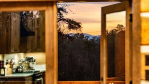 Eine rustikale Küche mit Holzausstattung und Blick auf eine bewaldete Landschaft im Abendrot.