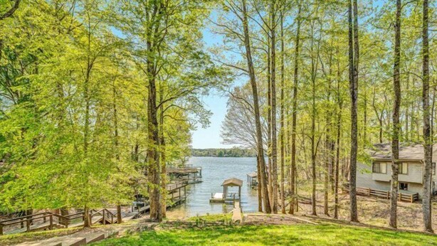 A lakeside cabin with a dock, surrounded by trees and a grassy area. - 3 Bedrooms, 1 Flex Rooms, 3 Bathrooms!  Lakefront Home with SUNSET VIEWS, located near Hales Ford Br (Moneta)