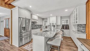 A modern kitchen with white cabinetry, a marble island, stainless steel appliances, and a wooden ceiling. - 3 Bedrooms, 1 Flex Rooms, 3 Bathrooms!  Lakefront Home with SUNSET VIEWS, located near Hales Ford Br (Moneta)