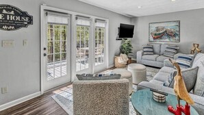 A spacious living room with a grey couch, a coffee table, and a mounted TV. - 3 Bedrooms, 1 Flex Rooms, 3 Bathrooms!  Lakefront Home with SUNSET VIEWS, located near Hales Ford Br (Moneta)