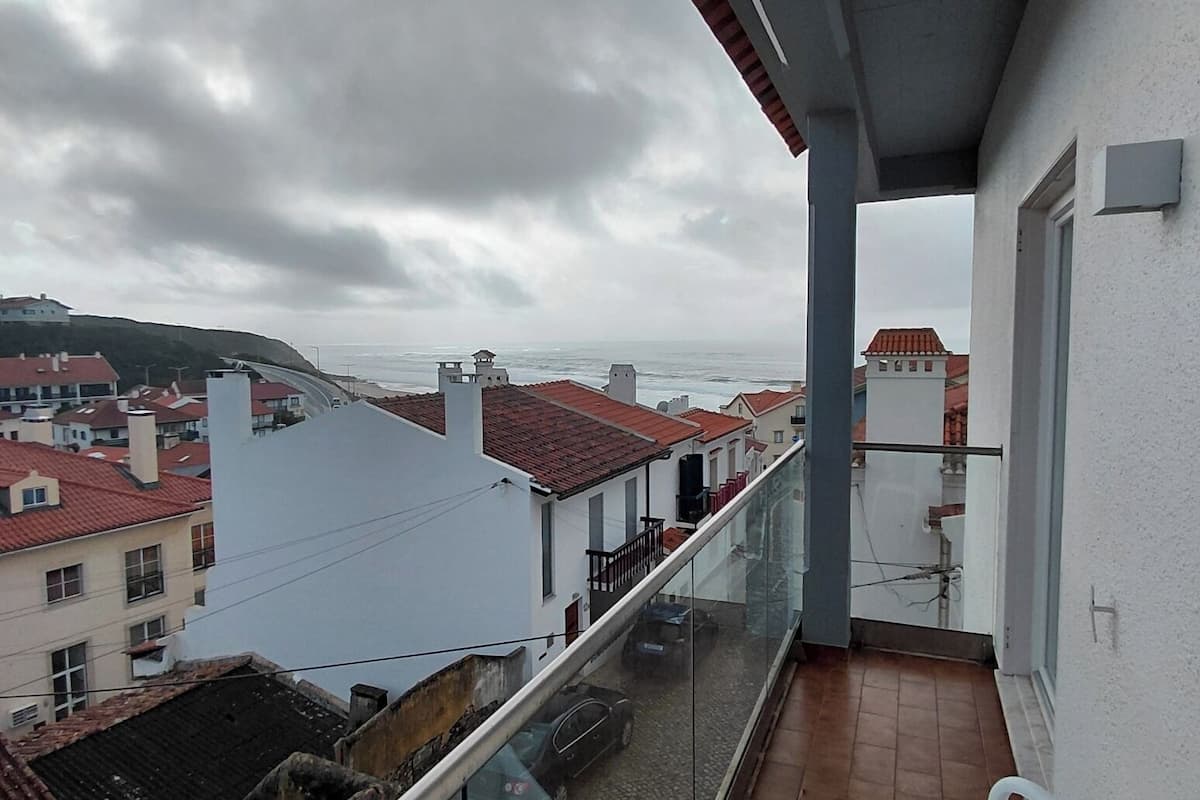 A balcony with a view of the sea and buildings.