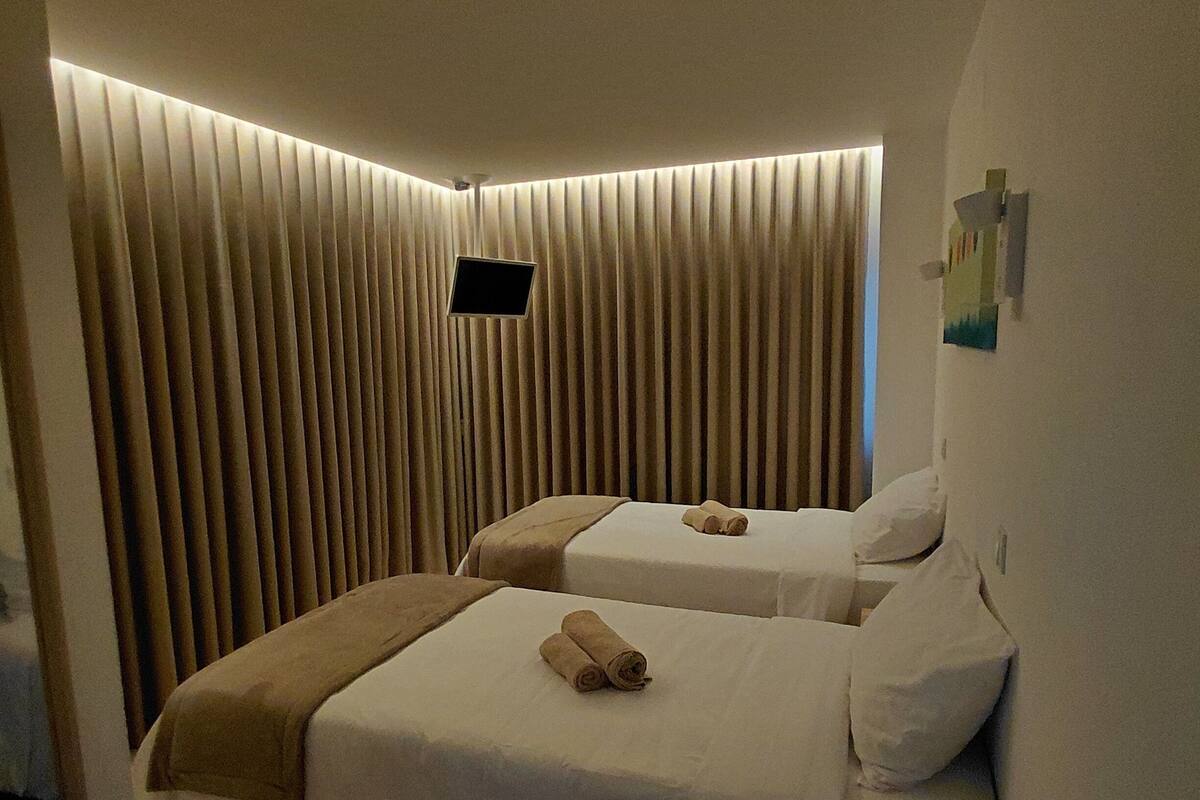 A hotel room with two beds, a flat-screen TV, a wooden floor, and a wall-mounted artwork.
