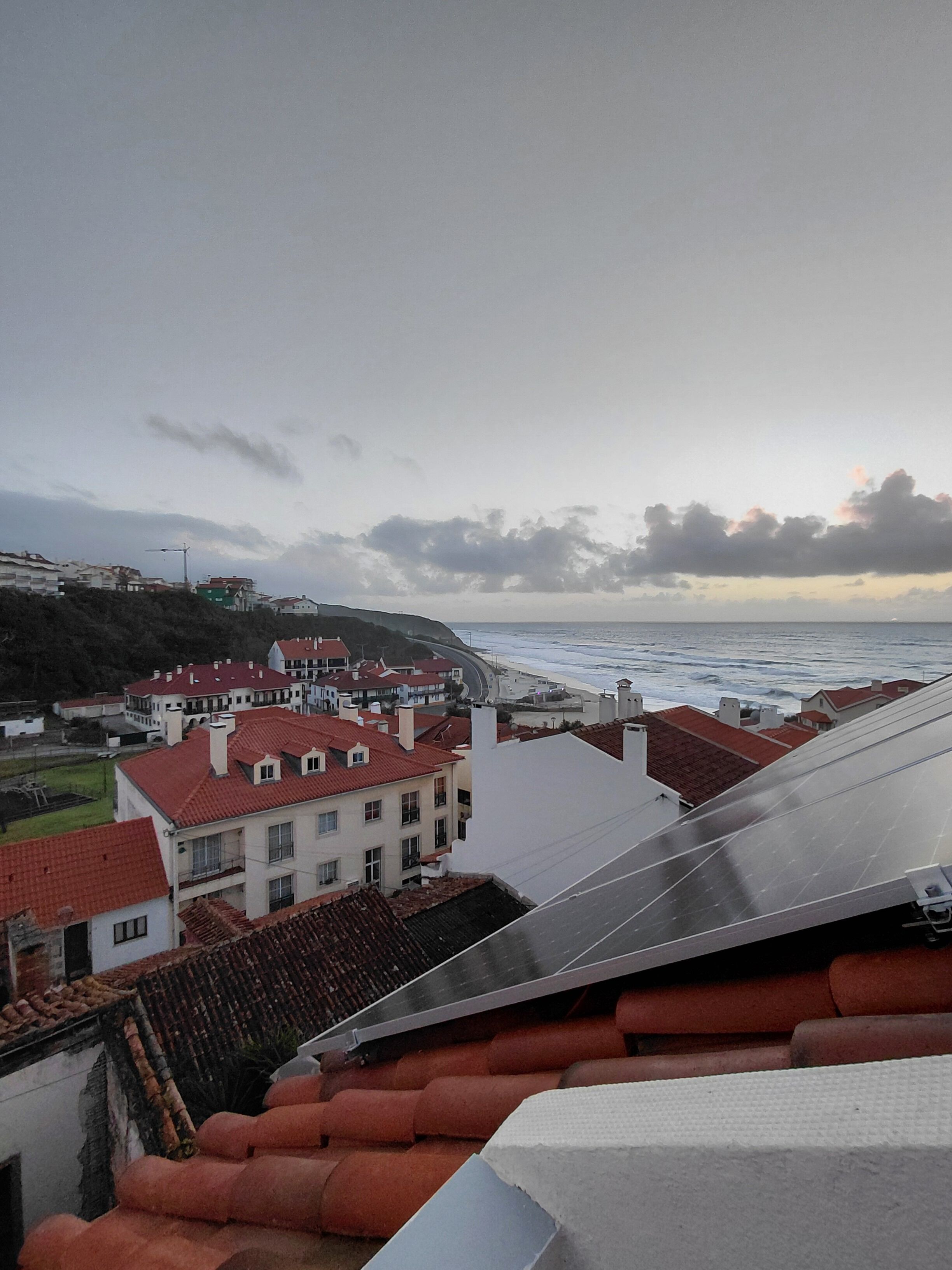 Un pueblo costero con edificios de techo rojo y vista al mar.